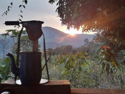 a coffee pot sitting on a table with a view of a mountain at Casinha Fulô do Bongue - 6 km from Serra dos Alves in Itabira
