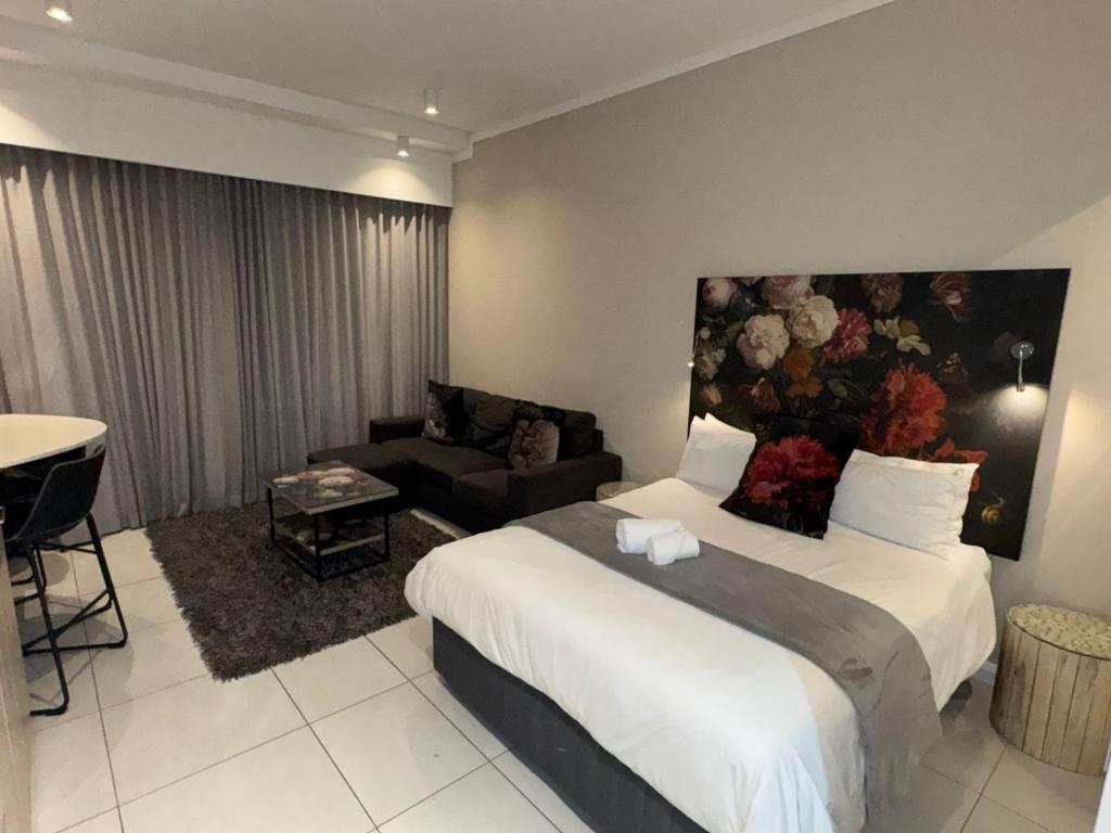 une chambre d'hôtel avec un lit et un salon dans l'établissement Menlyn Maine Residences 813, à Pretoria