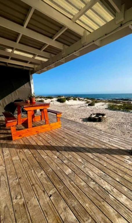 a wooden deck with a table on the beach at KaiKaiView in Port Nolloth