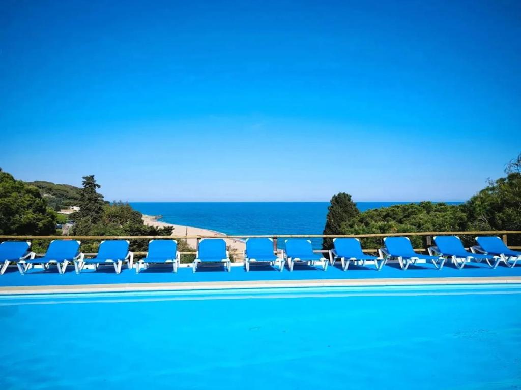 Una piscina con sillas y el océano al fondo. en Càmping Kanguro, en Sant Pol de Mar