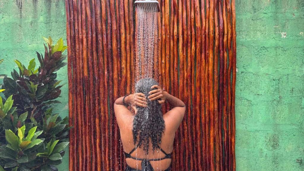 a man with long hair is in a shower at Outdoor Cinema Group Friendly Retreat in Pingwe