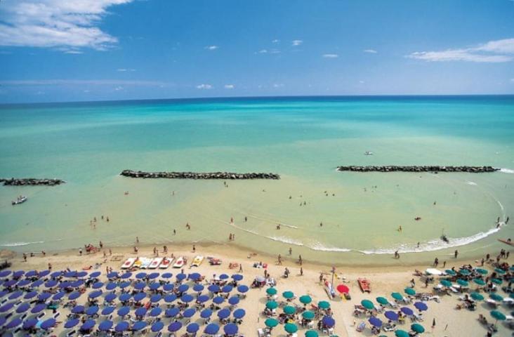 una playa con sombrillas y gente en el agua en Europa Apartment Centro, en Montesilvano