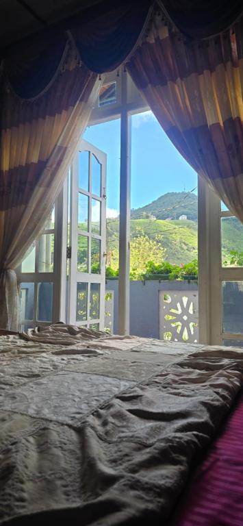 a bedroom with a bed and a large window at Mapelle House in Nuwara Eliya