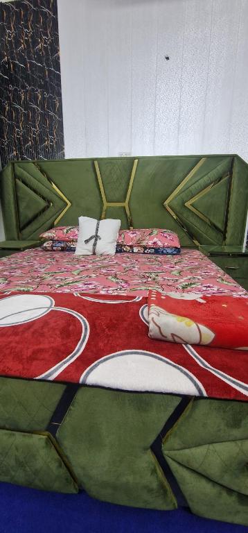 a bed with a red and green blanket on it at AL Imran villa in Lahore