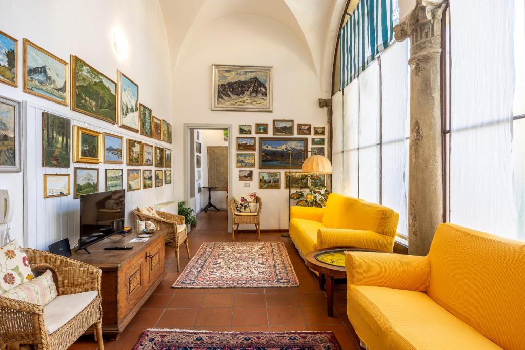 a living room with yellow chairs and a tv at Charme e storia apartment in Brescia center in Brescia