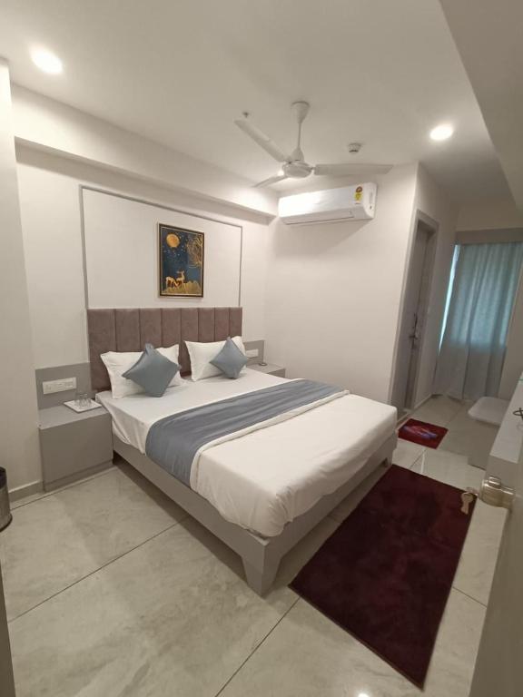 a bedroom with a large white bed with blue pillows at Hotel Royal Sky in Gandhinagar
