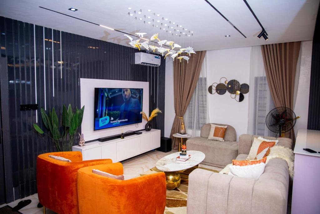 a living room with orange chairs and a flat screen tv at WHITNEY LUXURY APARTMENTs in Lekki