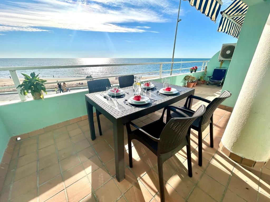 une table sur un balcon avec vue sur la plage dans l'établissement GATU PREMIUM Villa Isabel TERRAZA,PARKING,1ºLINEA PLAYA,WIFI,VISTA AL MAR, à Cadix