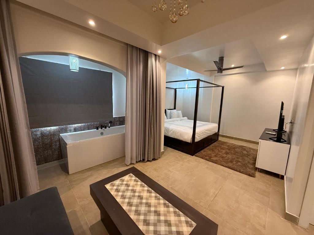 a bathroom with a tub and a bed and a mirror at Pajaros Luxury Suites in Calangute