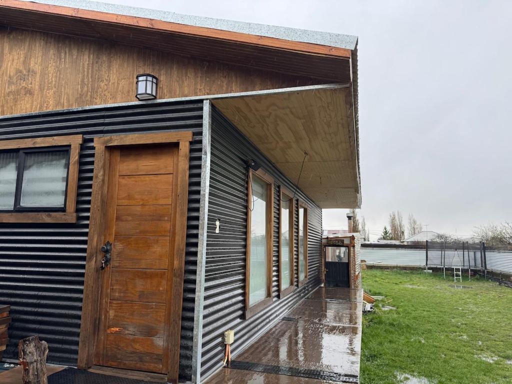 ein Haus mit einer Holztür an der Seite in der Unterkunft Aur House in Puerto Natales