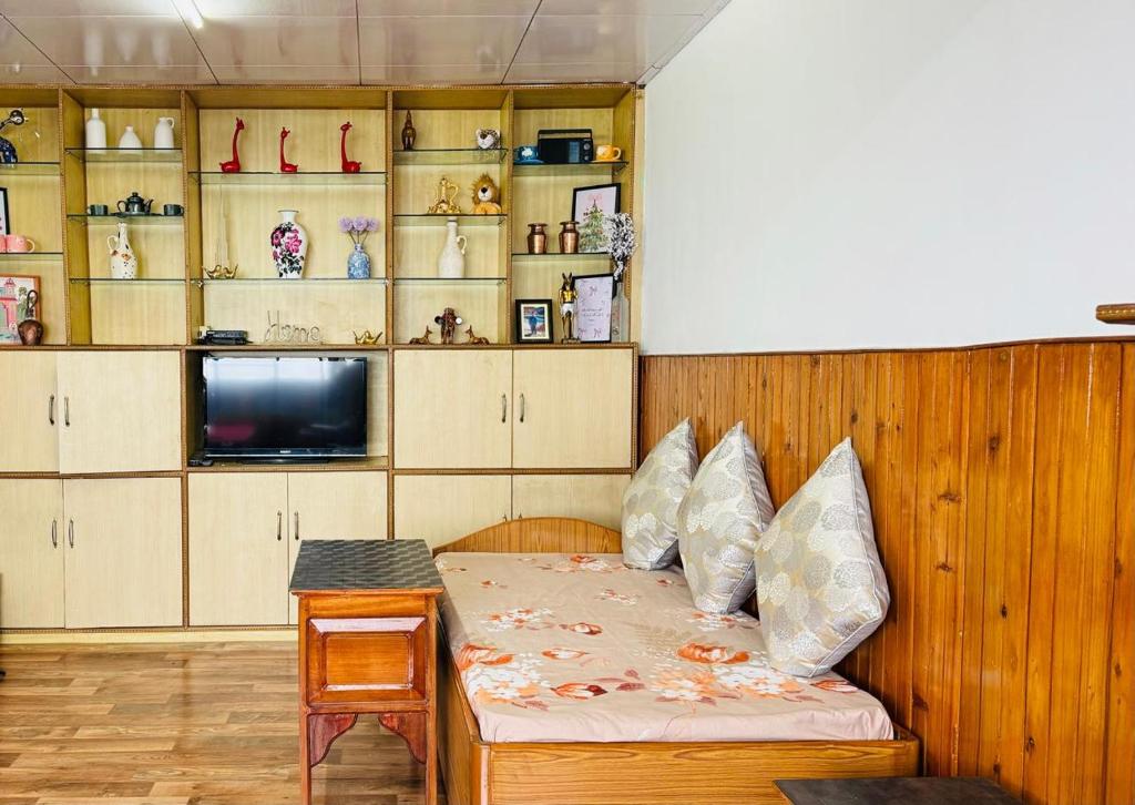 a room with a bed and a table and shelves at Tashi taksang homestay in Darjeeling