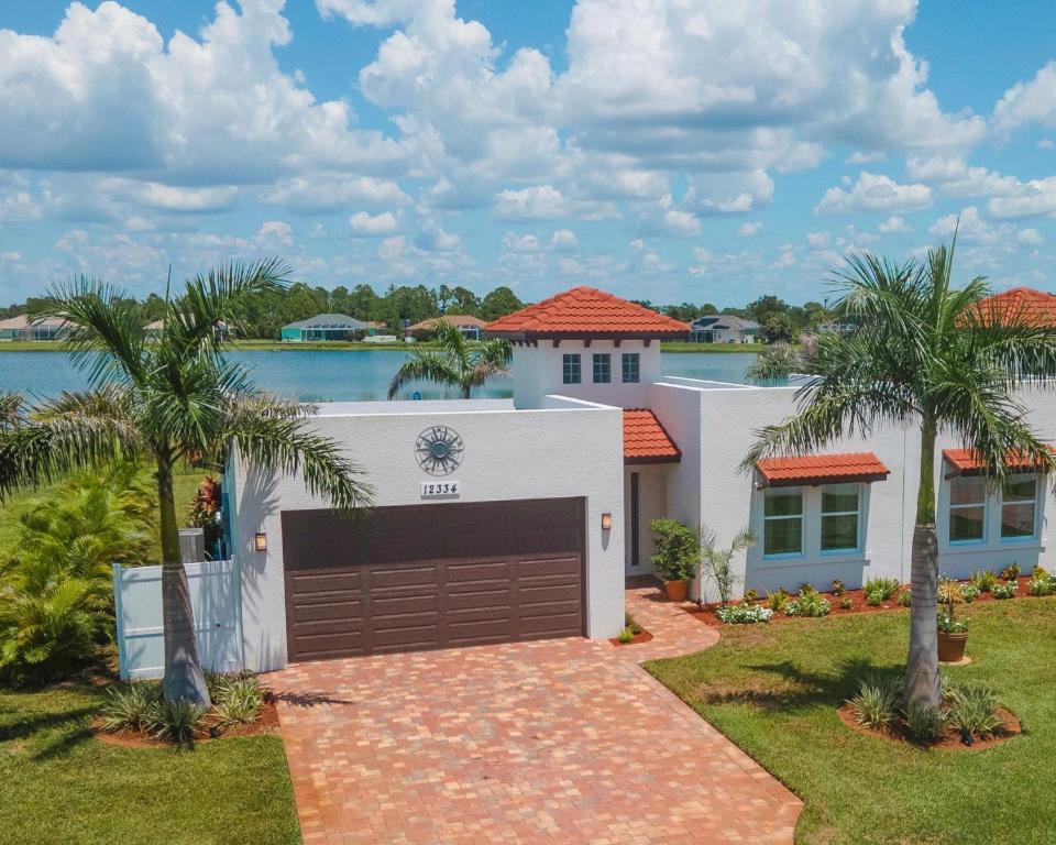 a white house with a garage and palm trees at Lake Marlin Villa 2 in Port Charlotte