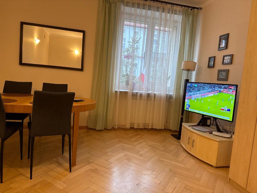 a living room with a table and a tv and a table and a television screen at Mieszkanie w Centrum in Białystok
