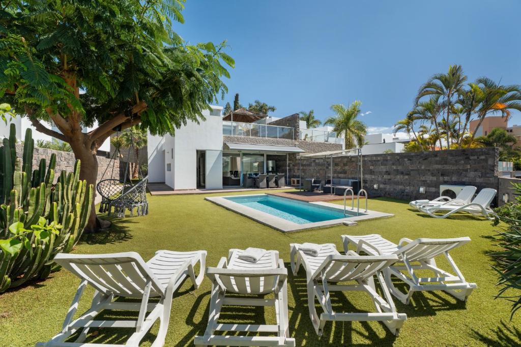 a yard with white chairs and a swimming pool at Villa Playa del Duque in Adeje