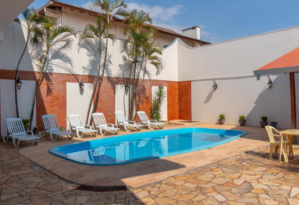 une piscine dans une cour avec des chaises et un bâtiment dans l'établissement Nana Suites, à Foz do Iguaçu