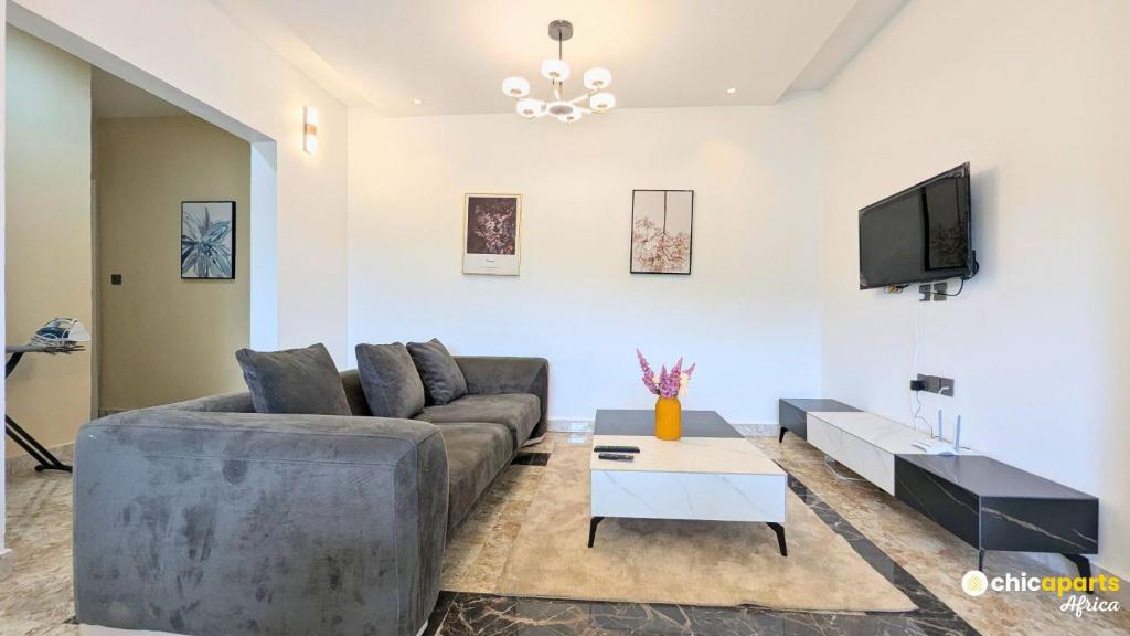 a living room with a couch and a tv at Chic & spacious studio with parking in Yaoundé