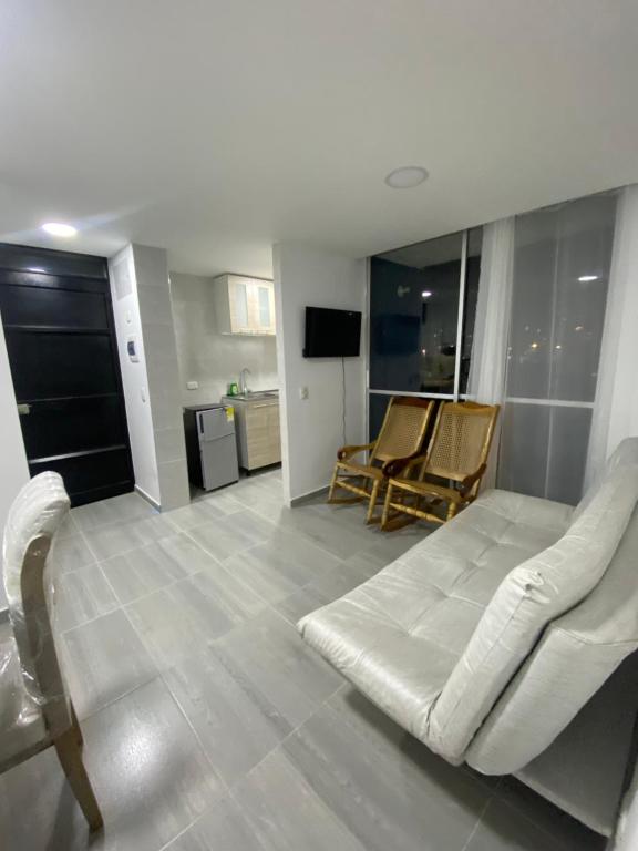 Una sala de estar con un sofá blanco y sillas. en Apartamento nevado reserva de curinca, en Santa Marta