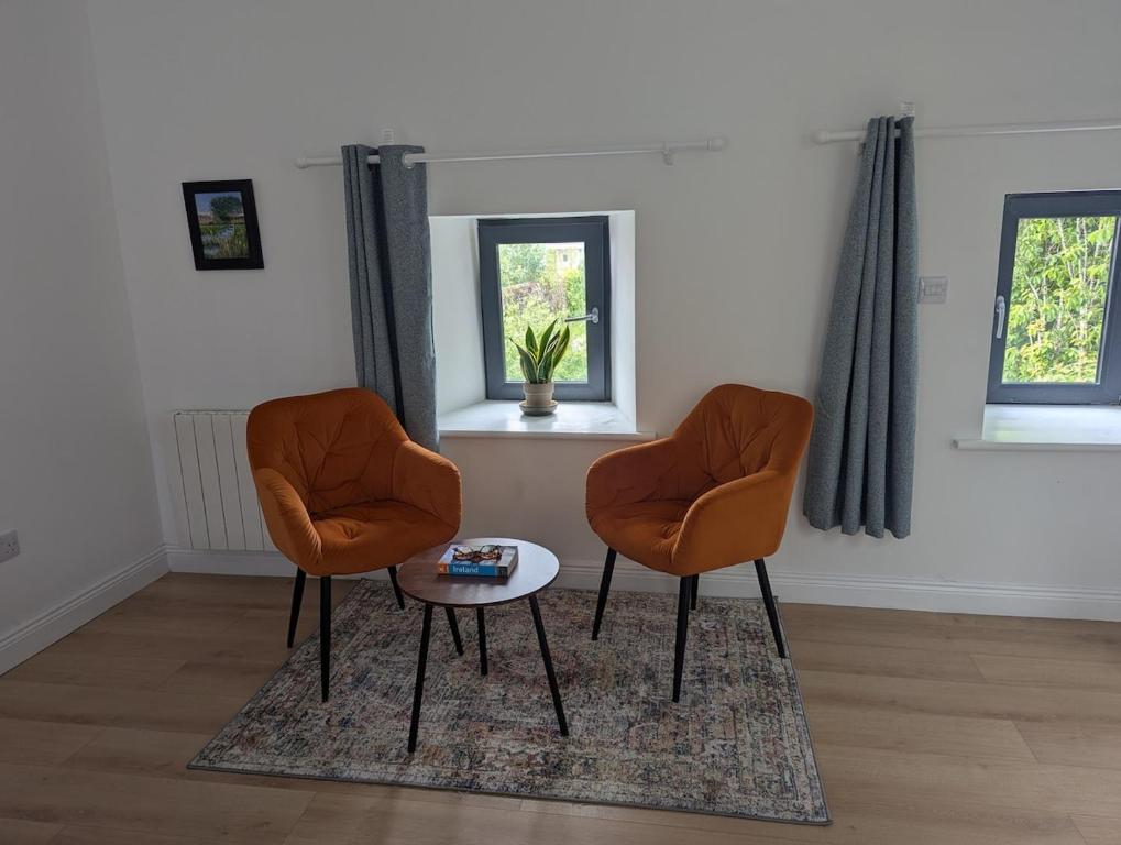 two orange chairs and a table in a room at The Coach House in Feevaghmore