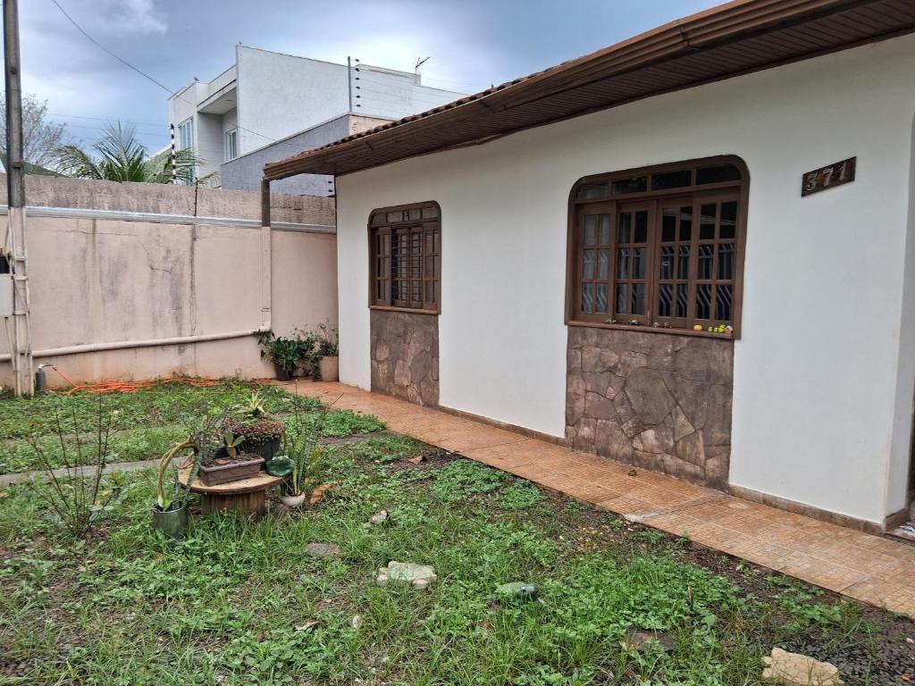 a white house with a yard with a fence and a door at Aconchego I in Foz do Iguaçu