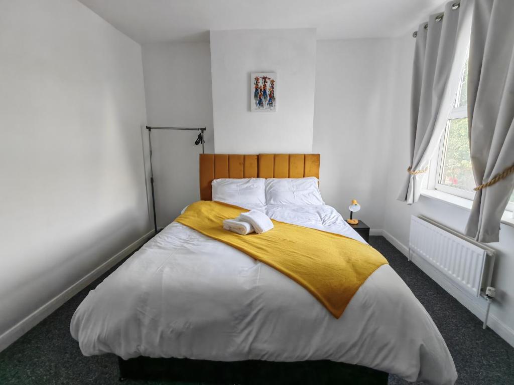 ウォルヴァーハンプトンにあるCentral Wolverhampton Stayの黄色い毛布が掛けられた大きなベッドのある寝室