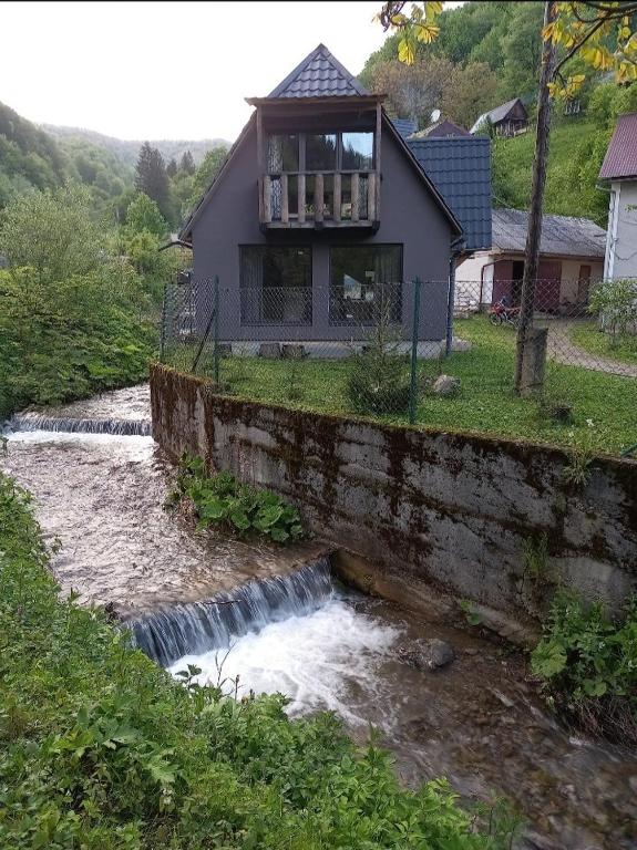 a house sitting on top of a stone wall next to a river at Pustirnik in Rakhiv