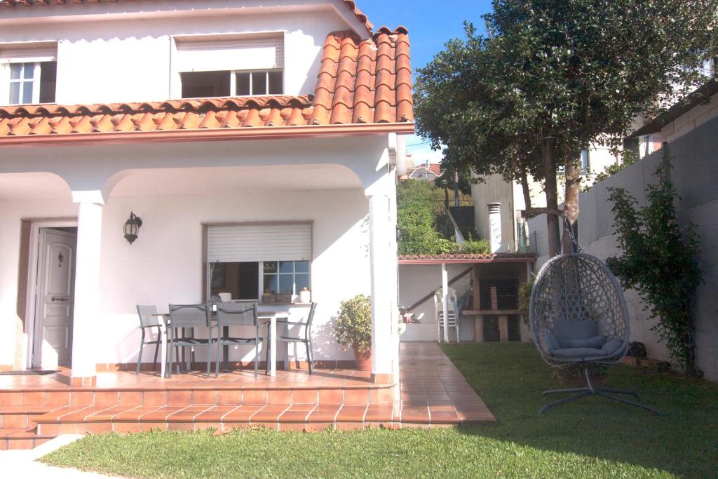 Casa blanca con patio con mesa y sillas en Playa de Cesantes, en Pontevedra