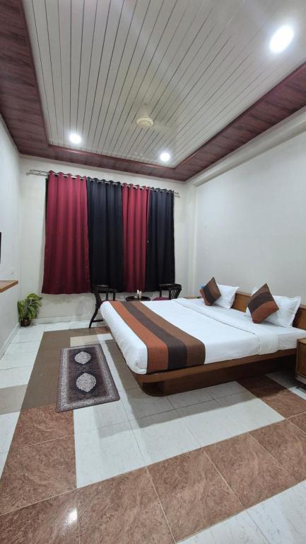 a large bed in a room with red curtains at Hotel dhola maru in Kota