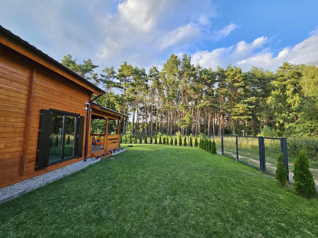 a backyard with a fence and a house at Domek przy lesie SPA in Niesulice