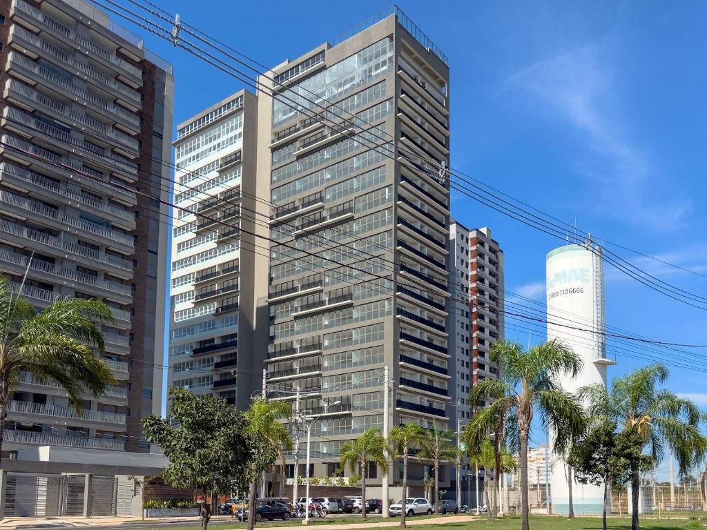 a tall building with palm trees in front of it at Condomínio Residencial Hype 017 - São José do Rio Pret in Sao Jose do Rio Preto