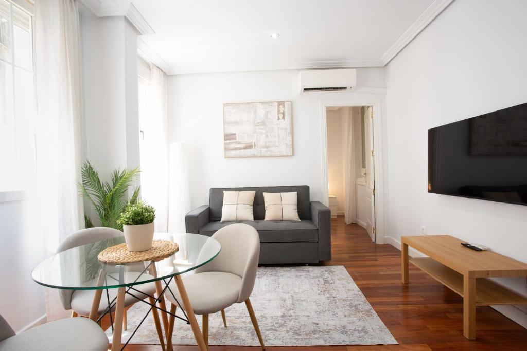 Una sala de estar con un sofá y una mesa de cristal. en Cozy 1BD Apartment in Alonso Martínez, en Madrid
