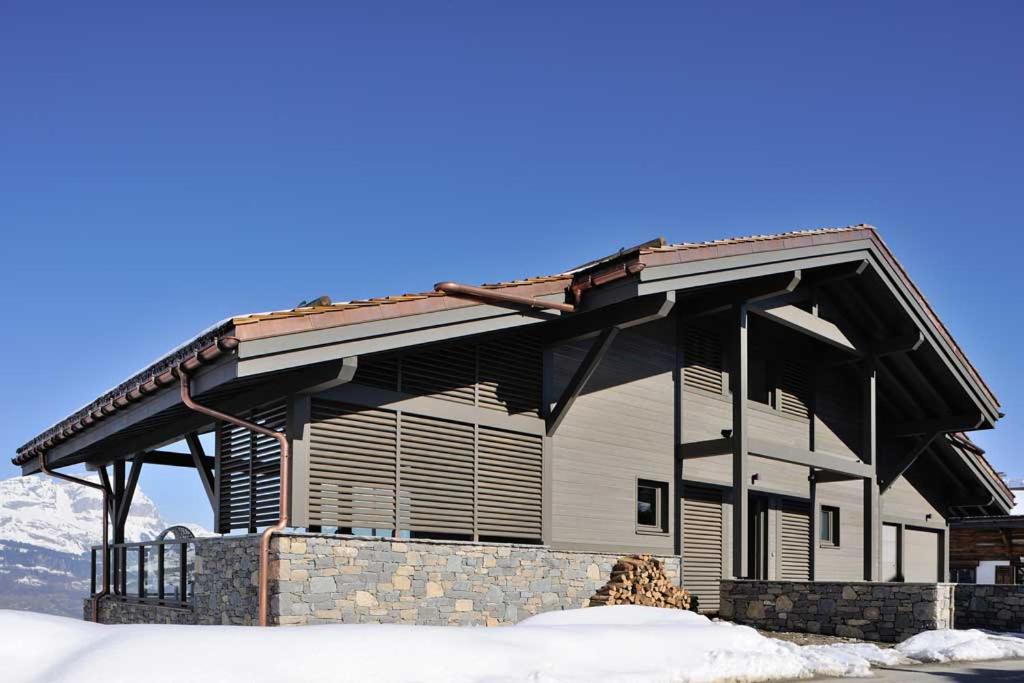 ein großes Gebäude mit einem Dach auf Schnee in der Unterkunft JAMES TAMG31 - luxury design chalet Megeve in Combloux