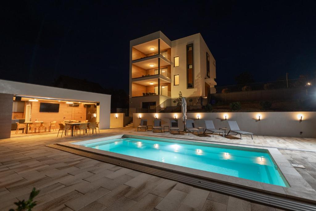 una piscina frente a una casa por la noche en Luxury apartments Villa Wood with spa and heated pool NEW, 