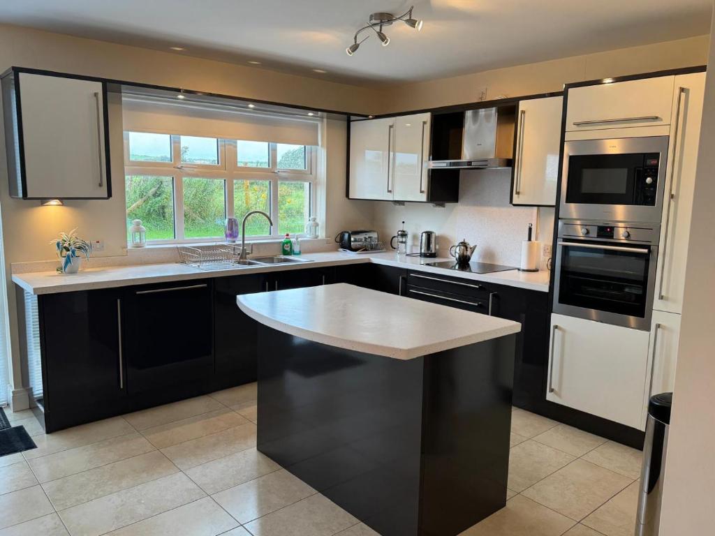 Una cocina con gabinetes negros y una encimera blanca. en Stonehaven, en Ballycastle