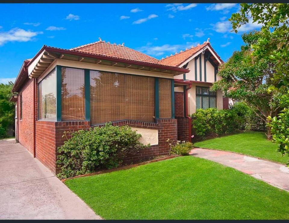 a red brick house with a green lawn at Haberfield House in Sydney