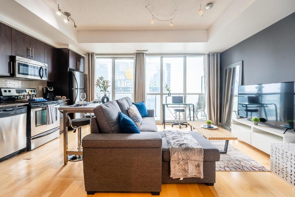 a living room with a couch and a kitchen at The Roland - Luxury Suite w Stunning City Views in Toronto