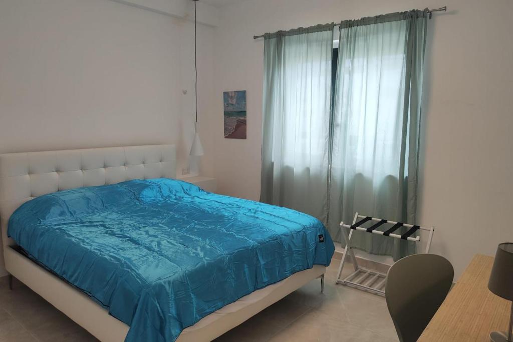 a bedroom with a bed with blue sheets and a window at Apartment - Sleeps 4 - Pool - Parking in SantʼAndrea Apostolo dello Ionio