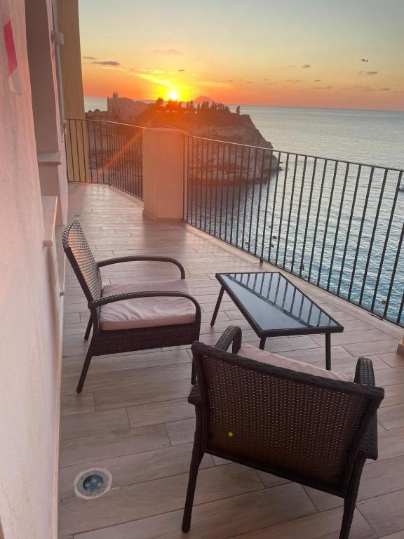a balcony with two chairs and a table and a sunset at Seaside Soul in Tropea