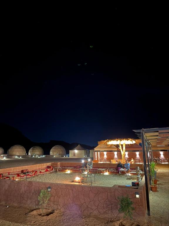 a beach at night with chairs and umbrellas at Nala Luxury Camp & Jeep Tours in Wadi Rum
