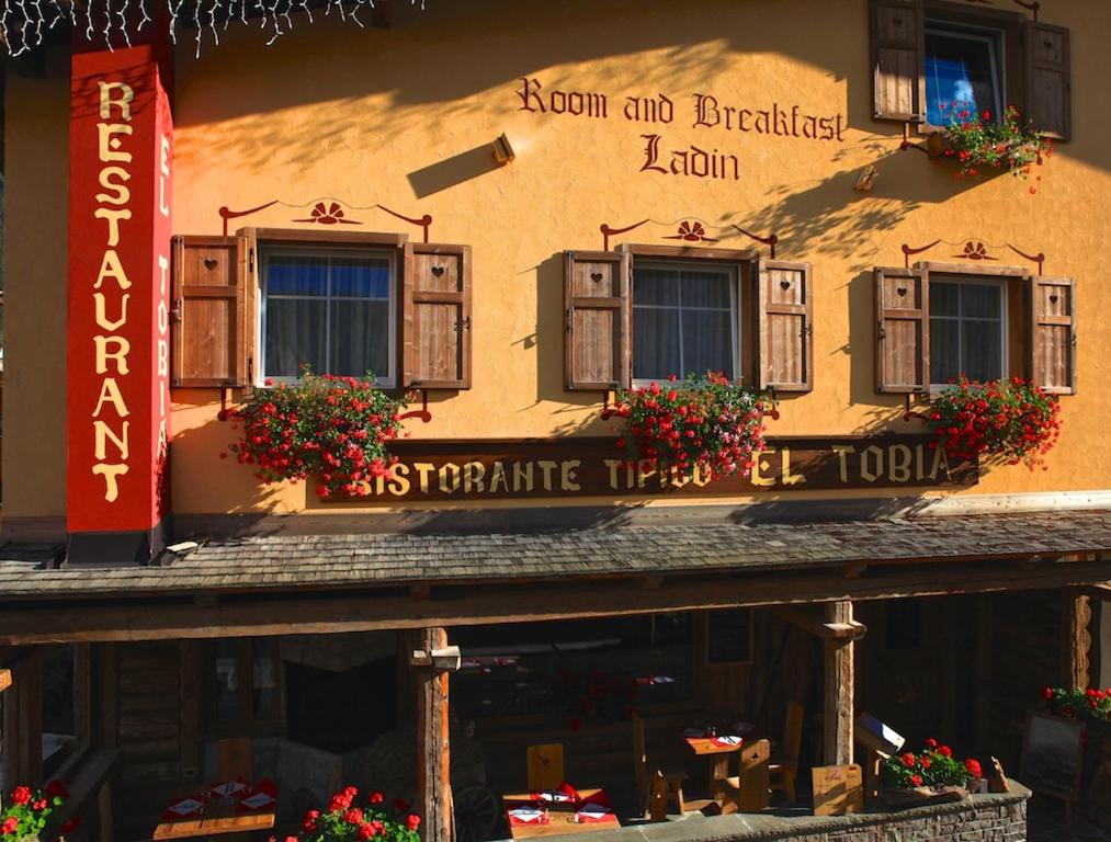 a building with a sign on the side of it at Garnì Ladin in Vigo di Fassa