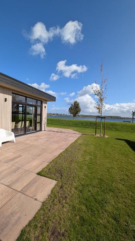 a building with a grass field and a tree at Maison du Lac in Lathum