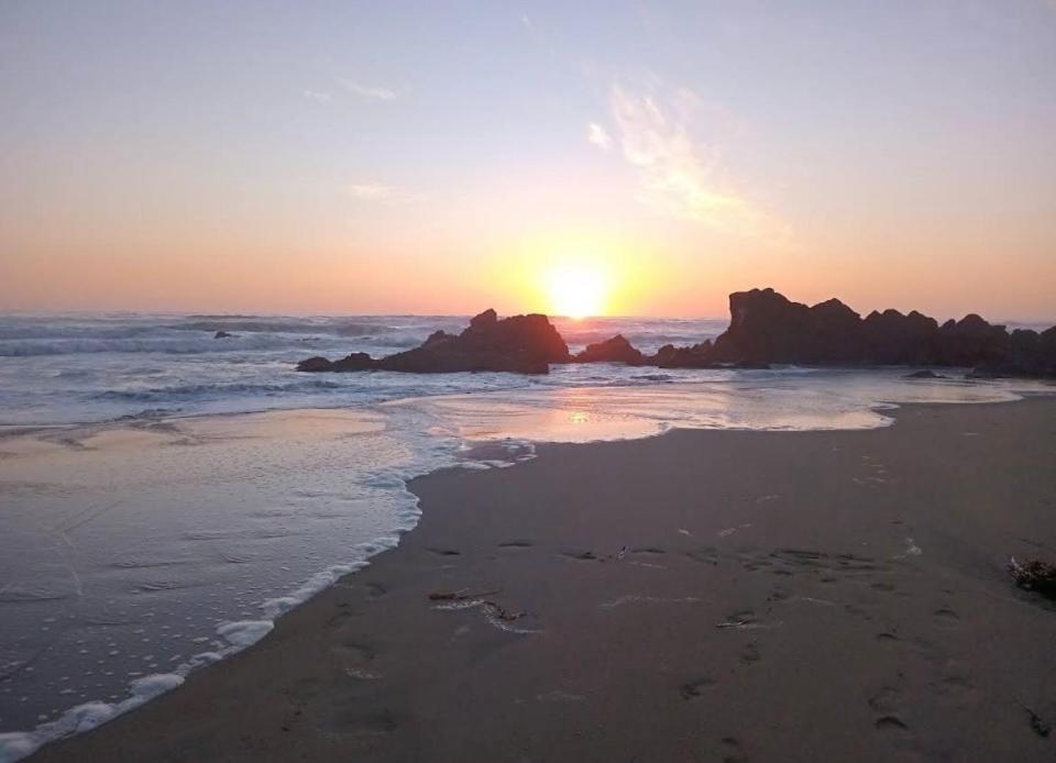 a sunset on a beach with rocks in the ocean at tiny house frente al mar in Guaquen