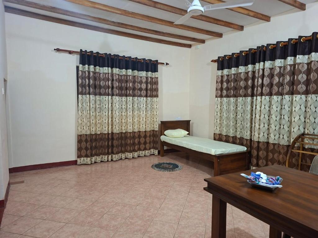 Habitación con mesa, banco y cortinas. en Sivaji House for Daily rent, en Dehiwala