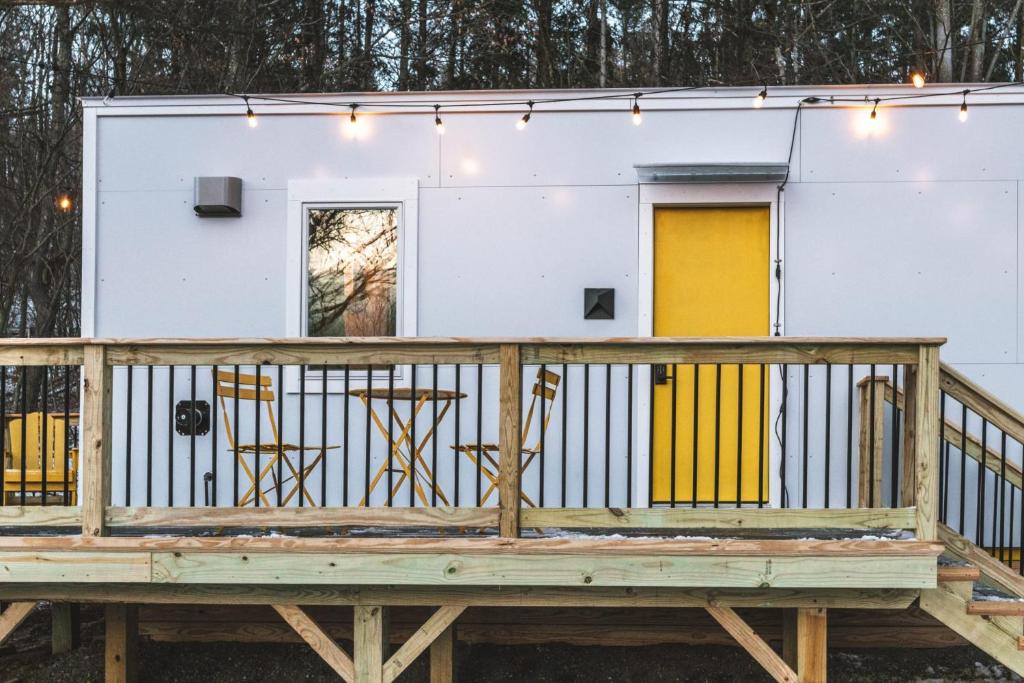 Una pequeña casa en una terraza con una puerta amarilla. en Modern Tiny House with hot tub & river near Stowe, en Johnson