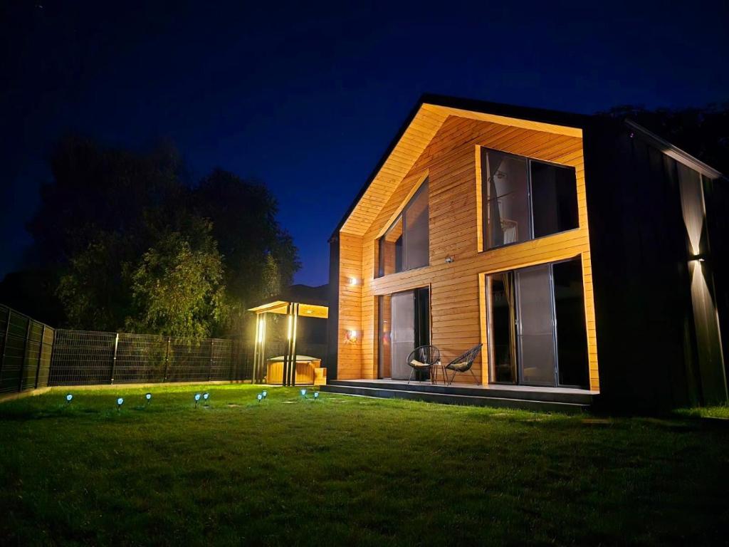 a house with lights on the lawn at night at Cabana Tei-Tei in Izvoarele