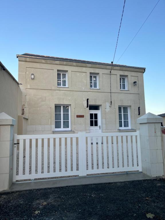 a white fence in front of a house at LE ROUJOU Charmante maison tout confort au calme in Le Puy-Notre-Dame