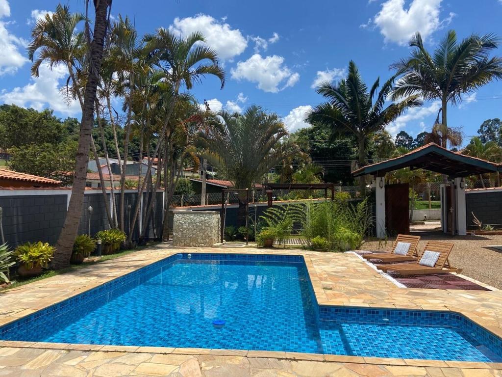 a swimming pool in a yard with palm trees at Casa de Campo no Circuito das Águas in Socorro