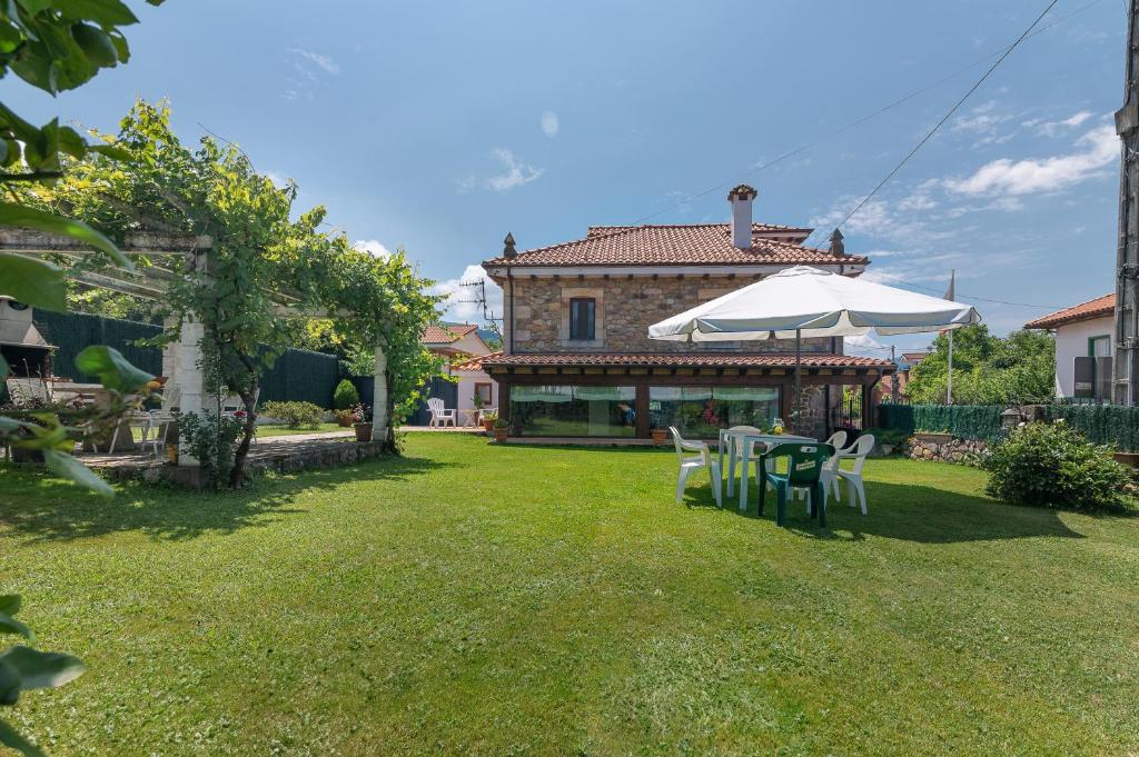 une maison avec une cour dotée de chaises et d'un parasol dans l'établissement Casa Rural La Venta, à Iruz