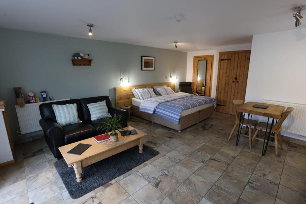 a bedroom with a bed and a couch and a table at Lynton Lodge Studios in Keswick