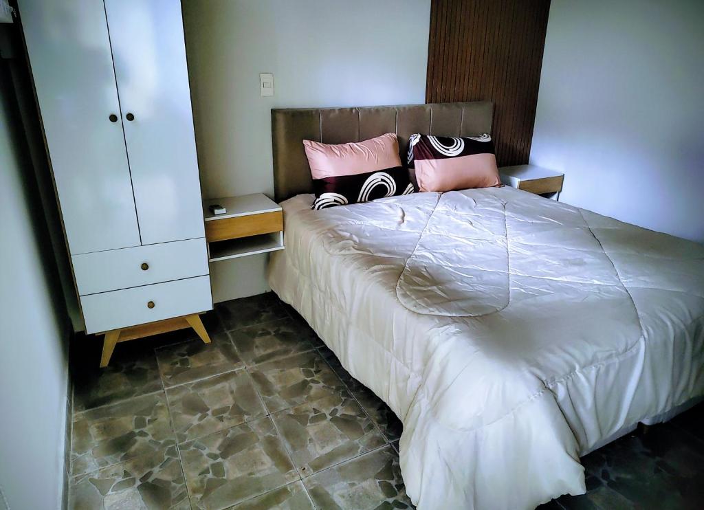 a bedroom with a large bed with pink and black pillows at Noah House Ezeiza in Ezeiza