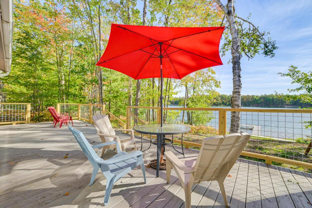 a patio with a table and chairs and a red umbrella at Private Dock, Near Skiing Lakefront Gaylord Home in Arbutus Beach